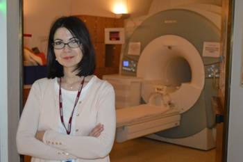Alexandra Touroutoglou stands in front of an MRI scanner